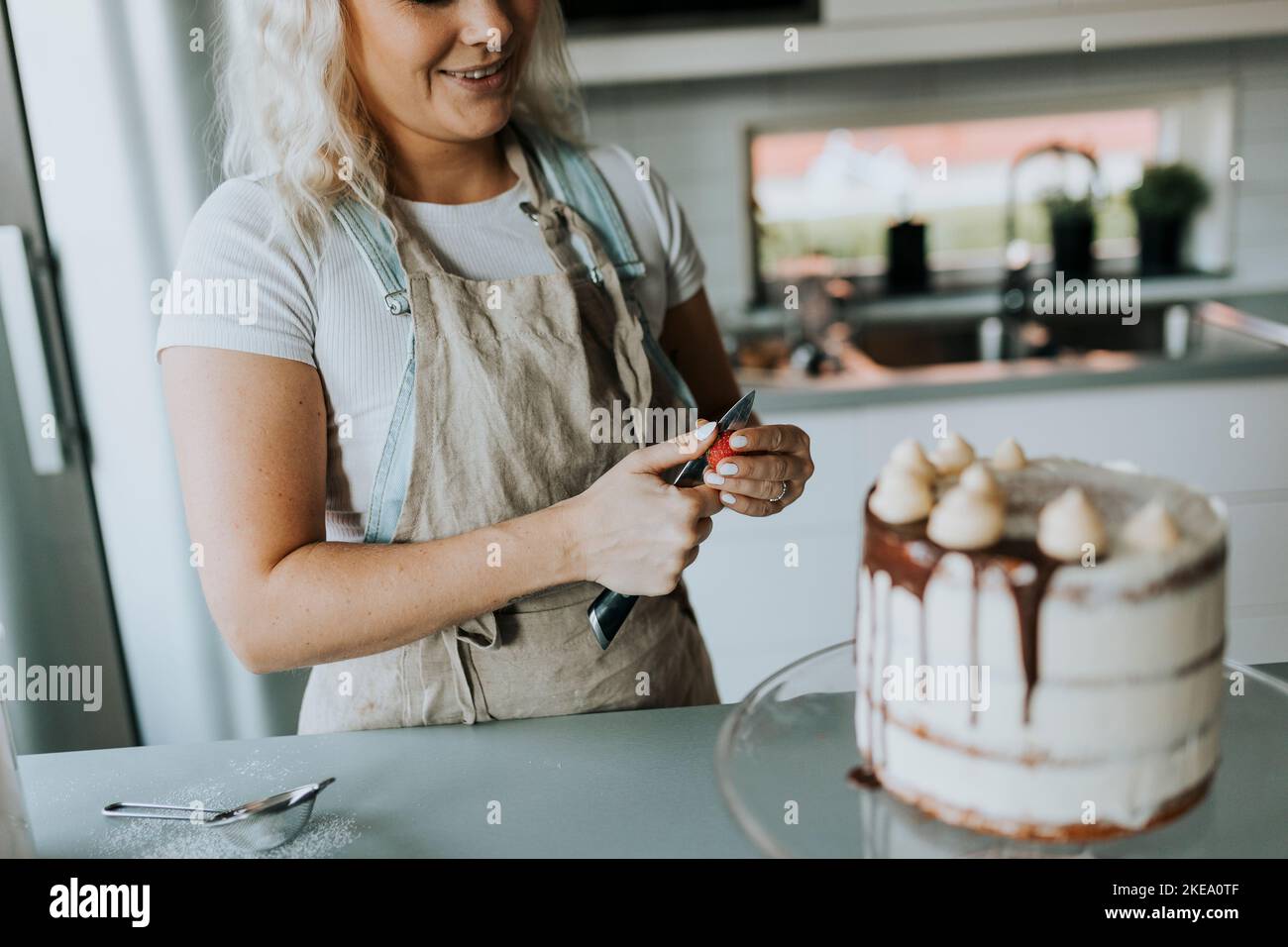 Woman in kitchen decorating cake Stock Photo