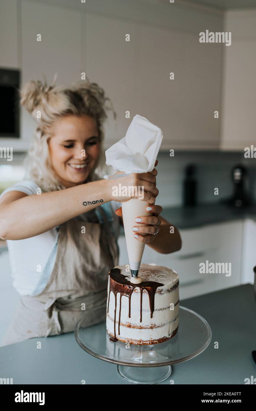 Woman in kitchen decorating cake Stock Photo Alamy
