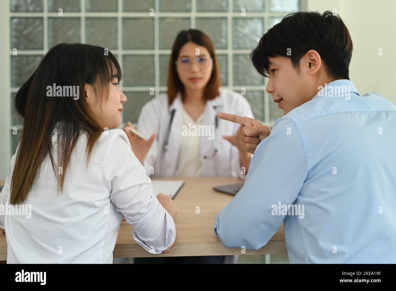 Back view of young couple arguing during family therapy counselling session with psychologist in clinic Stock Photo
