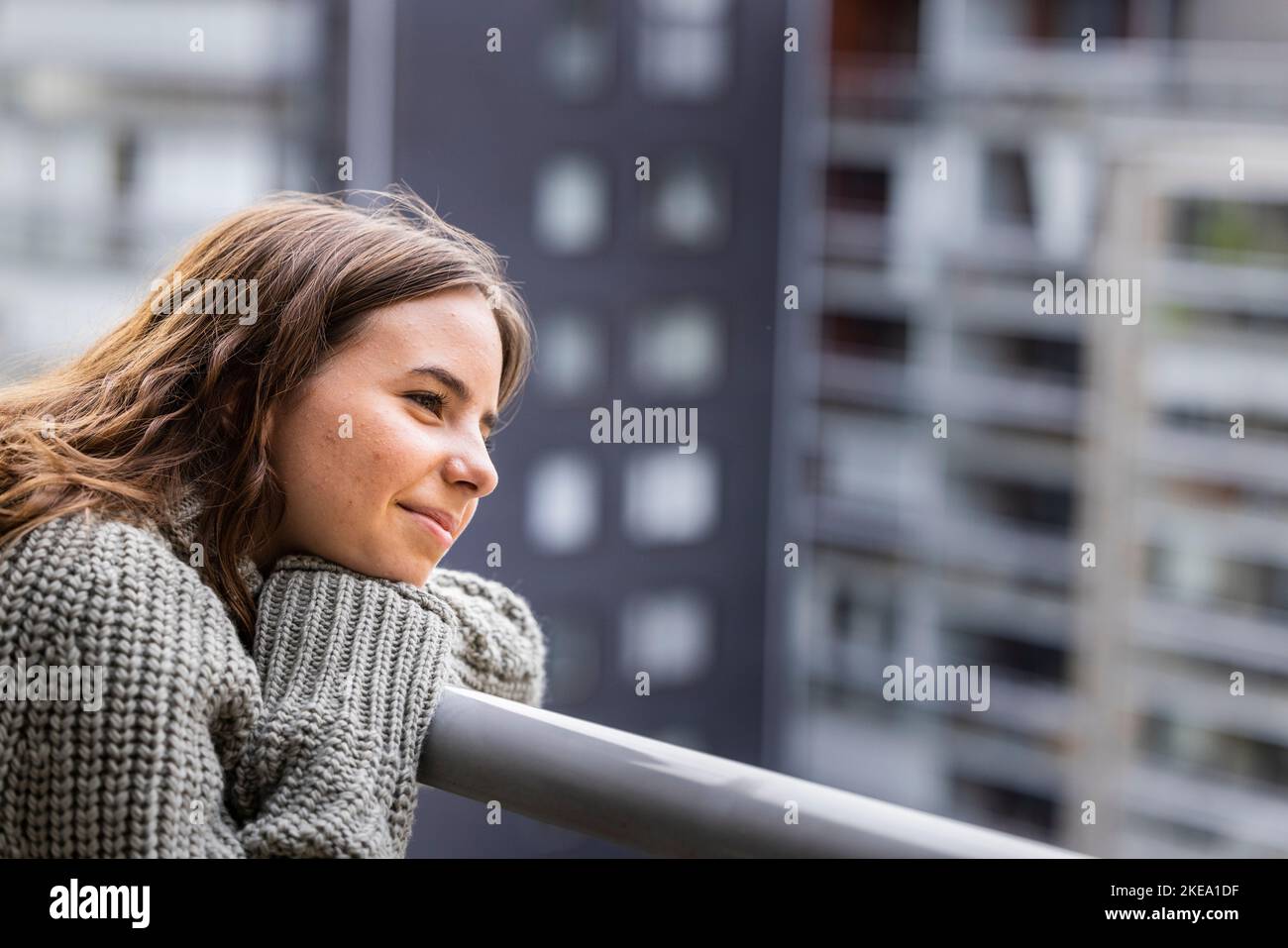 Smiling teenage girl looking at view from balcony Stock Photo