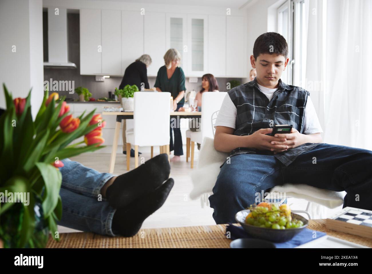 Teenage boy sitting in living room and using phone Stock Photo