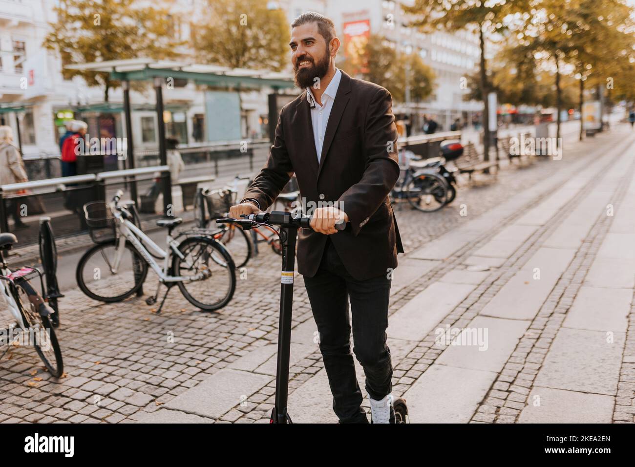 Smiling businessman using scooter Stock Photo
