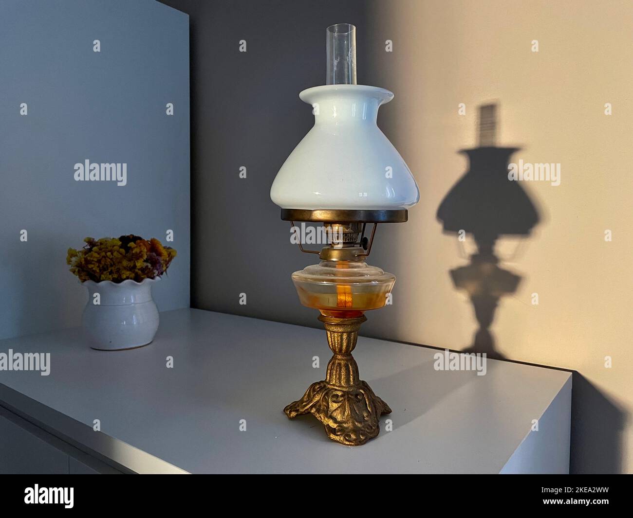 Beautiful vintage oil lamp with lamp shade made of white glass on a white Shadow of the