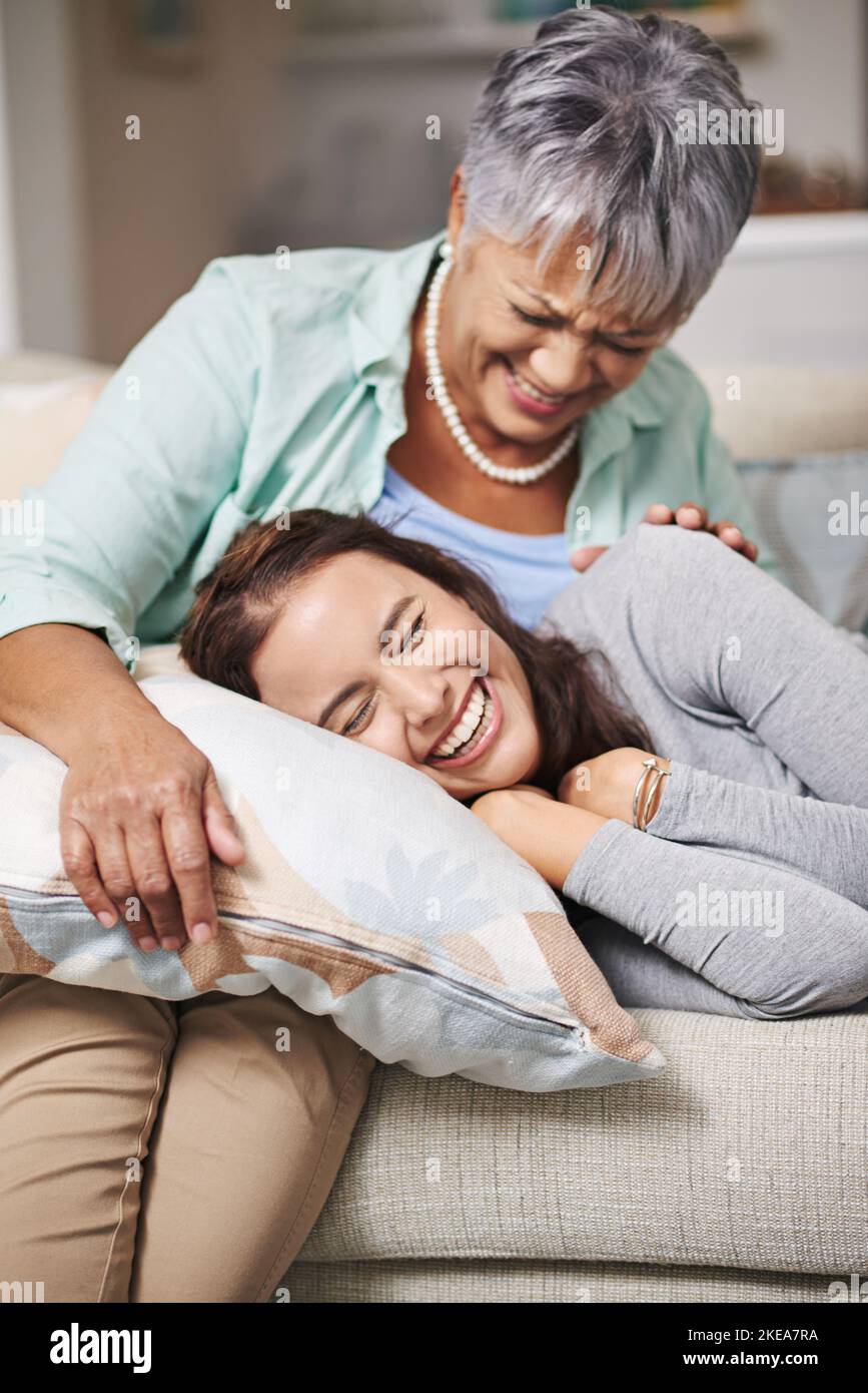 We havent done this since you were a little girl. a young woman resting with her head on her mothers lap in the living room. Stock Photo
