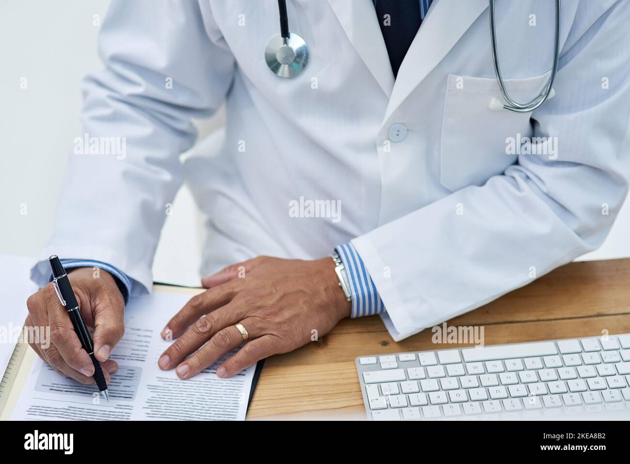 Working on some new medical research and development. Closeup shot of a doctor using a computer and making notes in an office. Stock Photo