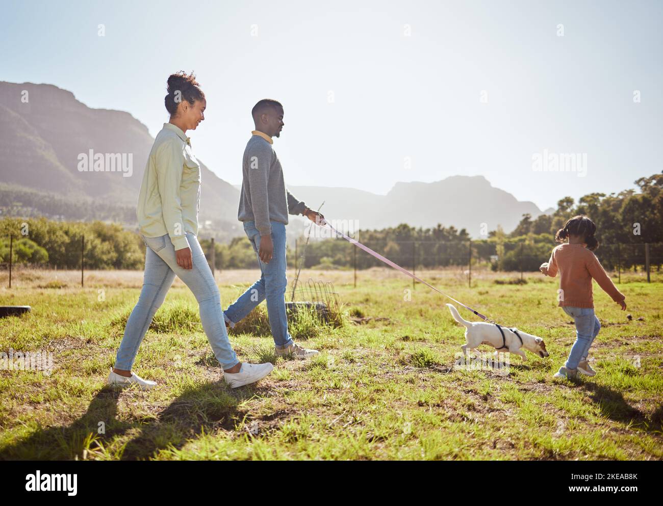 Nature, pet and black family taking a walk with dog having fun, bonding and enjoying summer. Love, animals and mom and dad walking with young girl and Stock Photo