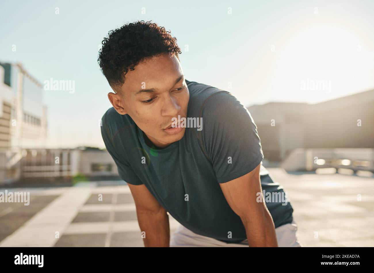 Runner, fitness and tired man in a city fatigue from running exercise, cardio workout or training. Breathing, fatigue and healthy sports athlete Stock Photo