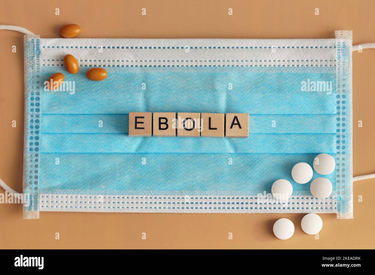 Ebola is laid out with wooden cubes on a surgical face mask. There are various pills lying around. Viral hemorrhagic fever. Stock Photo