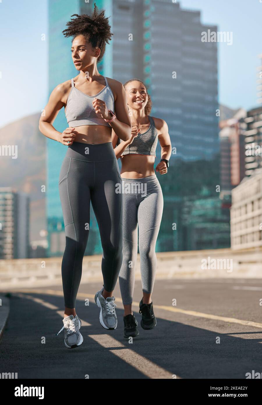 Fitness, exercise and friends running in the city together for an intense cardio workout in street. Sports, athletes and women runners doing outdoor Stock Photo