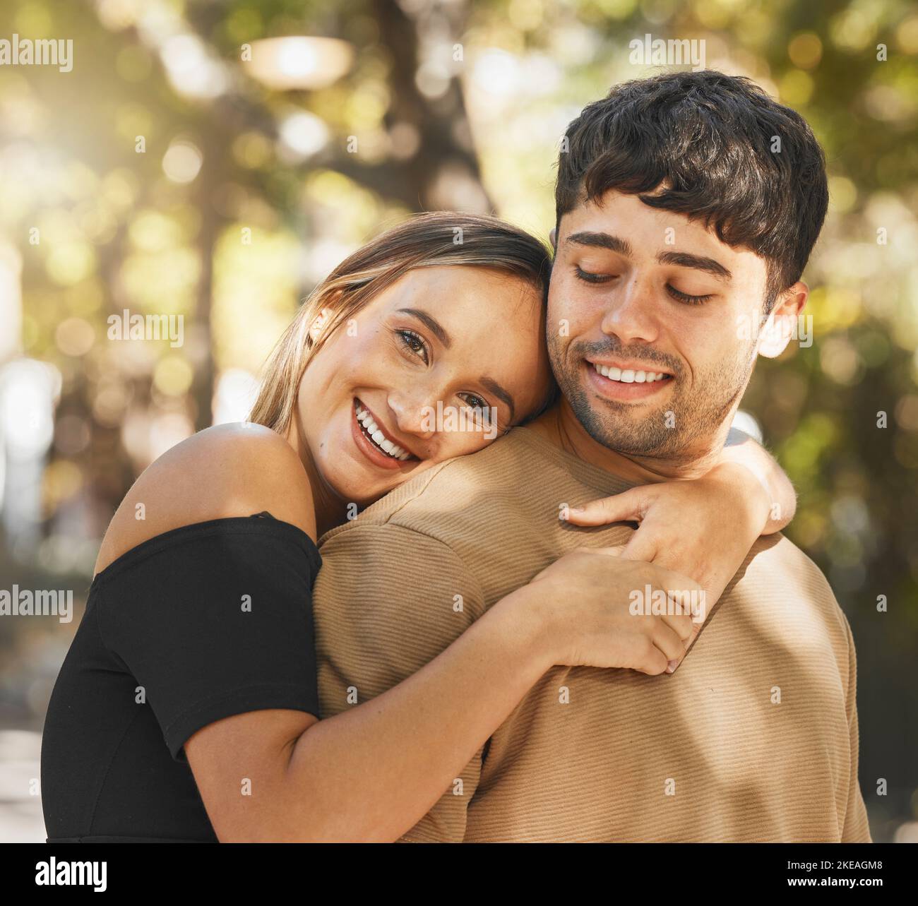 Love, couple and hug being happy, smile and romantic for relationship, bonding and outdoor together. Romance, man and woman embrace, being loving and Stock Photo