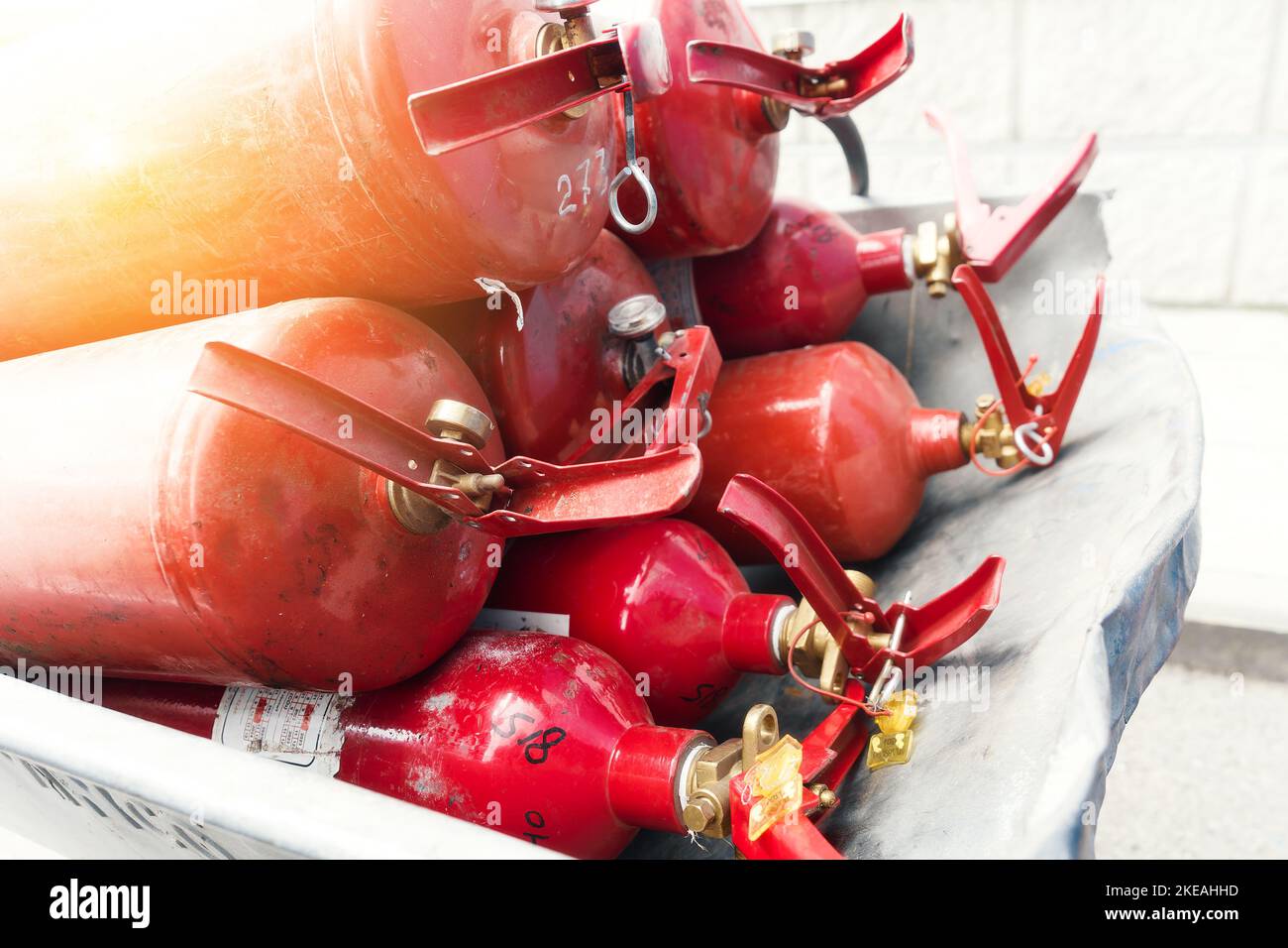 Many red fire extinguishers are lying in stack. Fire extinguishing equipment. Distribution of fire extinguishers for extinguishing fires.. Stock Photo