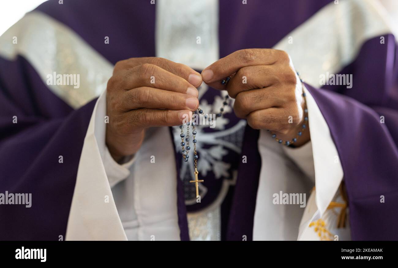 Priest, pastor and man hands with rosary with cross in church, prayer and catholic worship, praying or spiritual respect. Christian preacher, faith Stock Photo