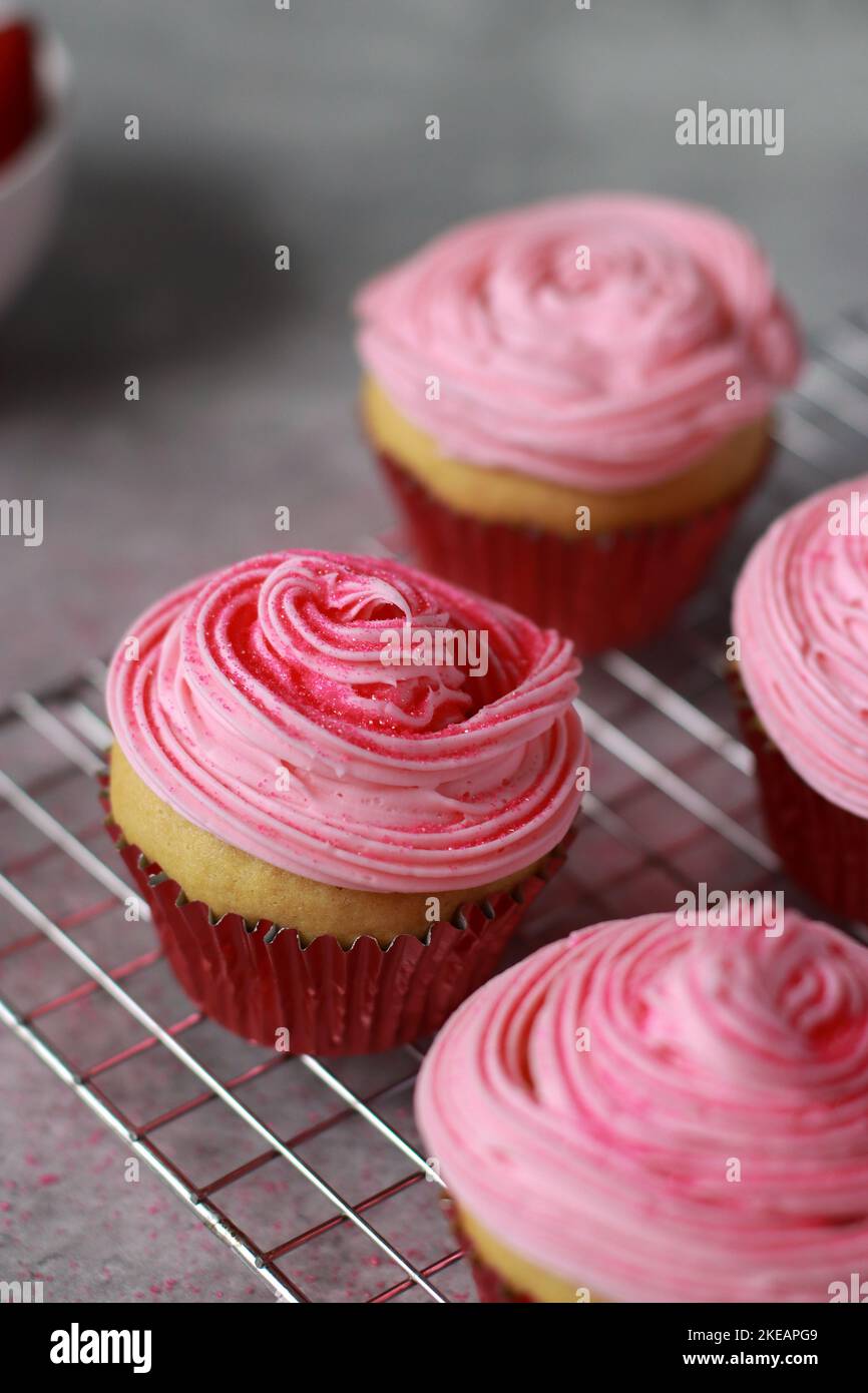 close up of vanilla muffins decorated with pink buttercream frosting on top Stock Photo
