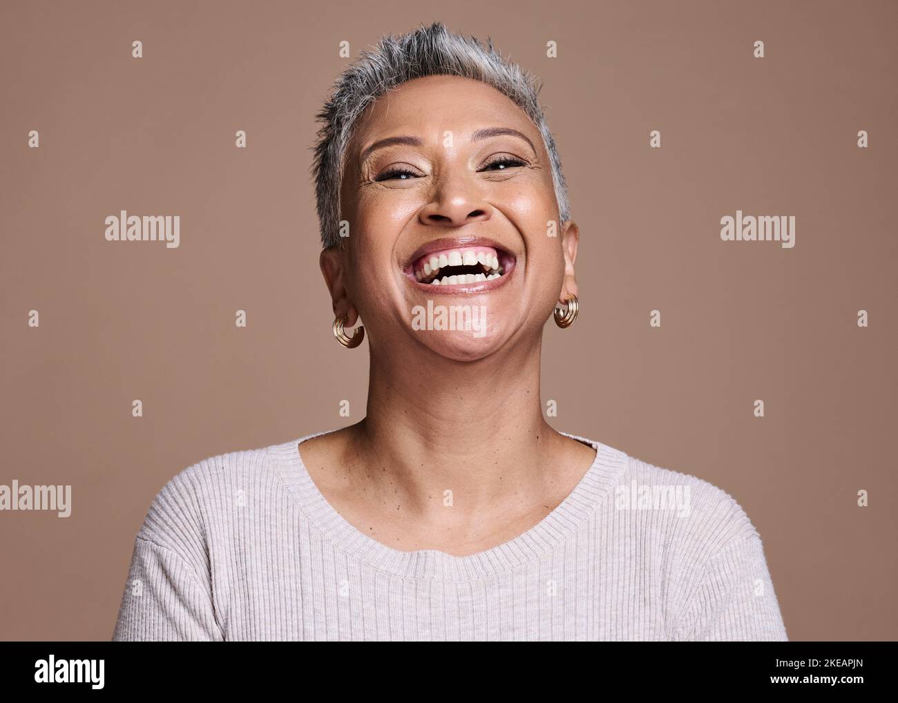 Black woman, beauty and happiness with a senior laughing about funny joke or memory on a brown studio background. Face portrait of a mature model Stock Photo