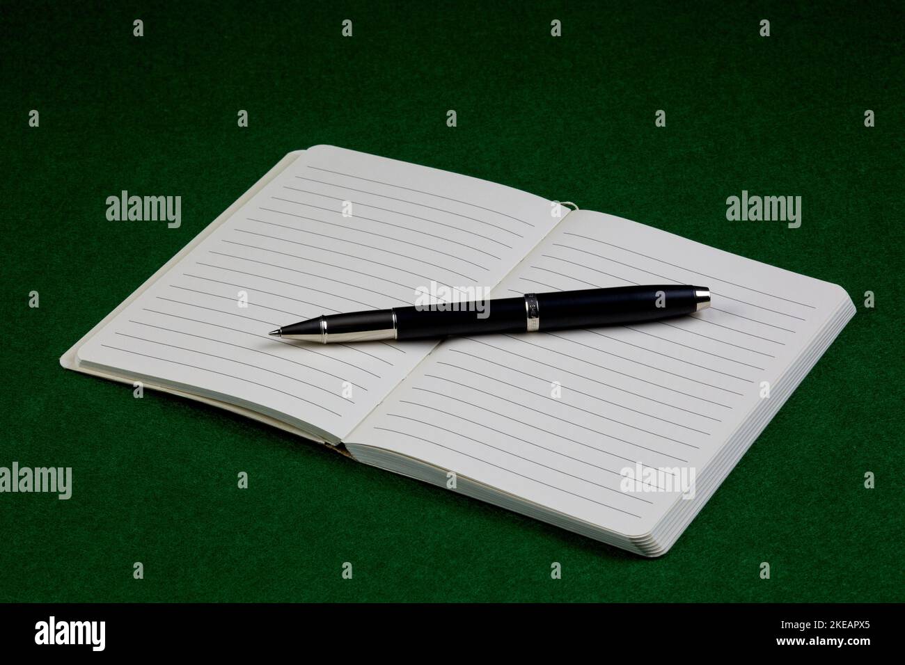 Rollerball pen and open notebook on a felt table cover Stock Photo