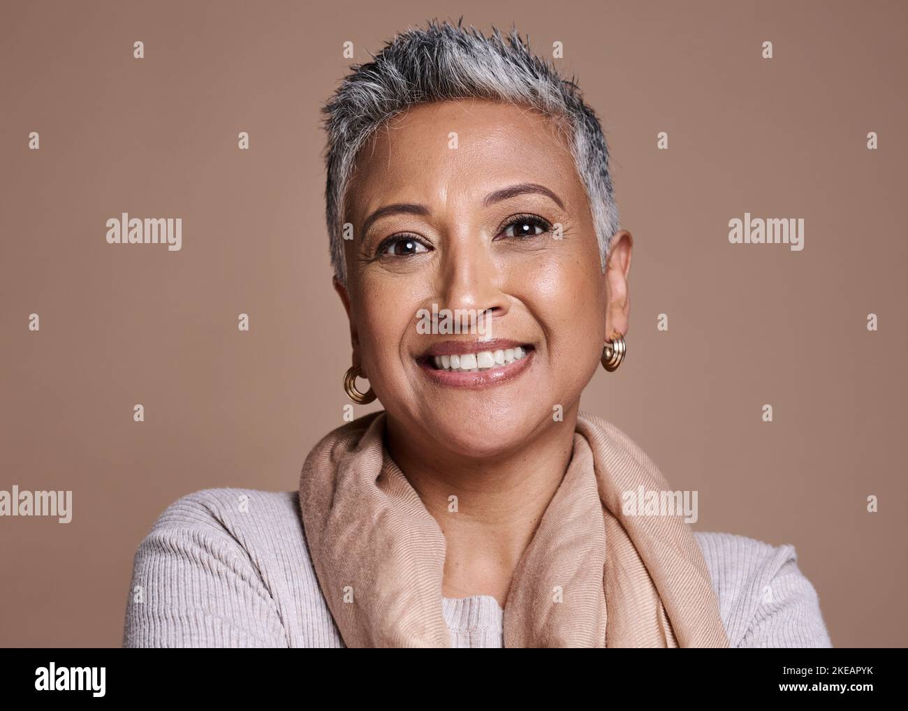 Face, fashion and senior woman in studio isolated against a brown background. Beauty portrait, smile and makeup cosmetics or aesthetics of happy Stock Photo