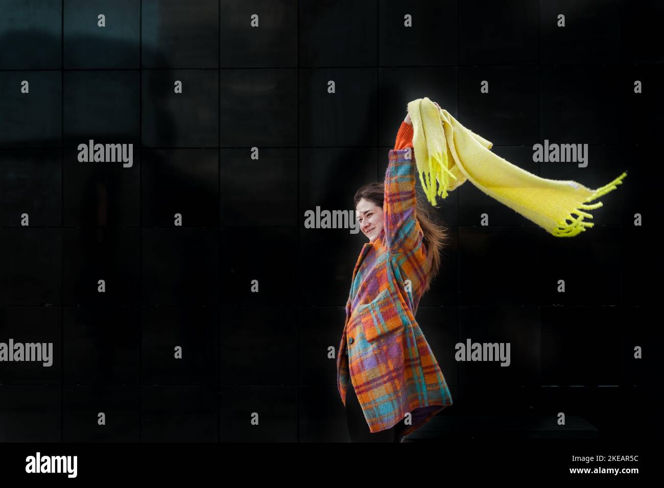 Young woman with yellow scarf in the windy in winter city Stock Photo