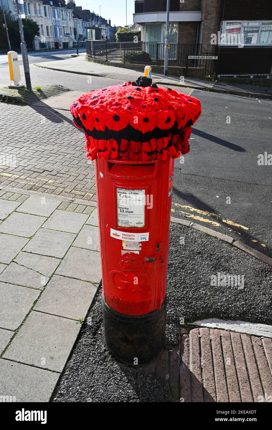 Brighton UK 11th November 2022 - A knitted poppy covering has appeared (yarn bombing) on post box in the Queens Park area of Brighton on Armistice Day in the UK . The Armistice, an agreement to end the fighting of the First World War as a prelude to peace negotiations, began at 11am on 11 November 1918 : Credit Simon Dack / Alamy Live News Stock Photo