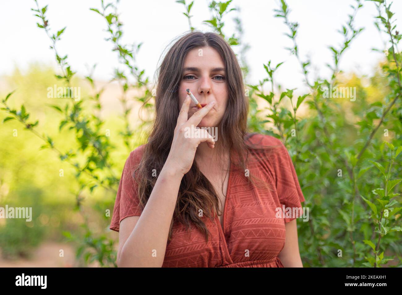 Happy young woman smoking in the countryside Stock Photo