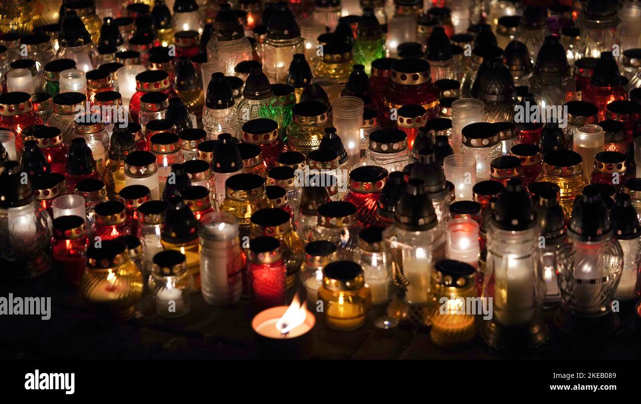 Lot of burning candles at night in cemetery.Glass inextinguishable