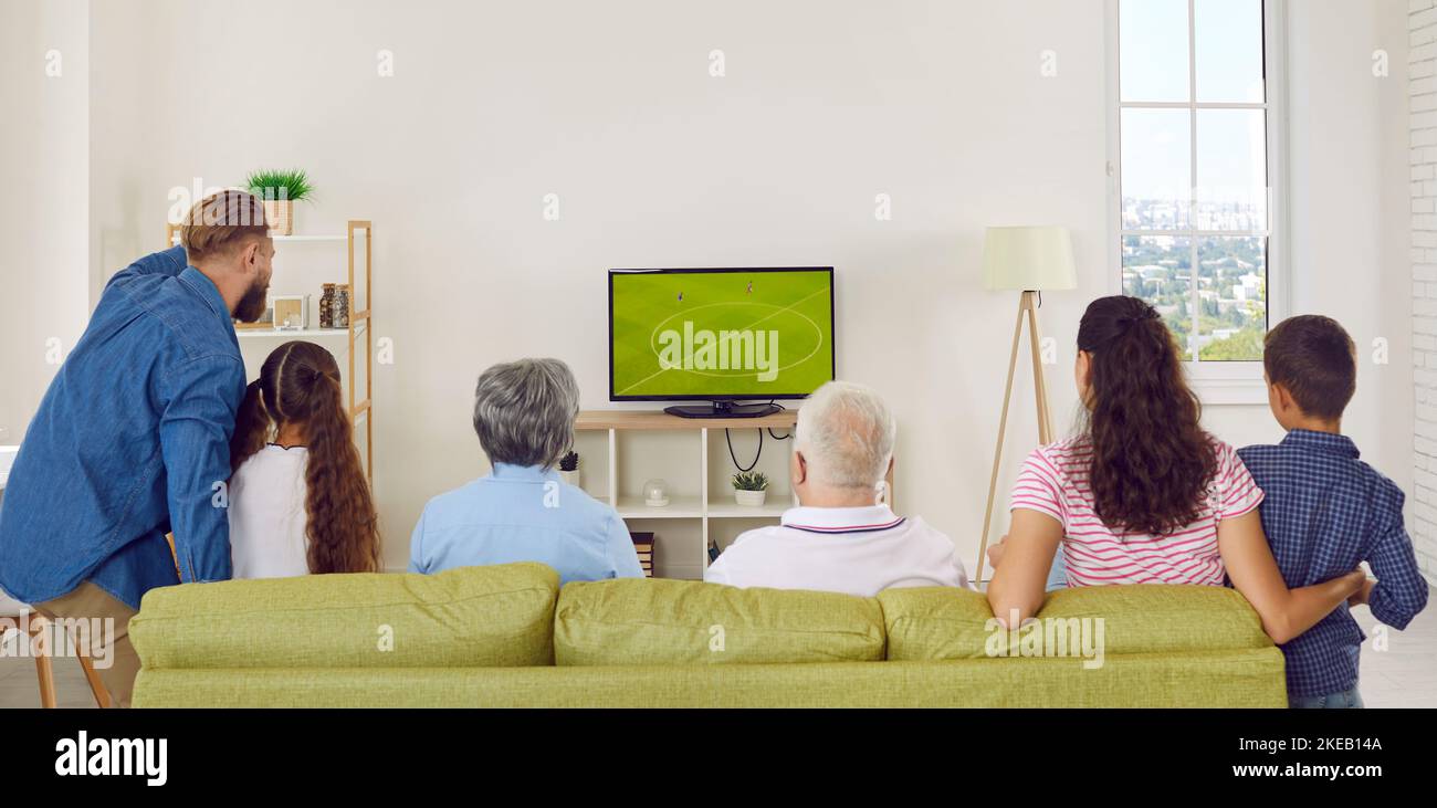 Big multi-generational family cheering while watching soccer match on TV at home. Stock Photo