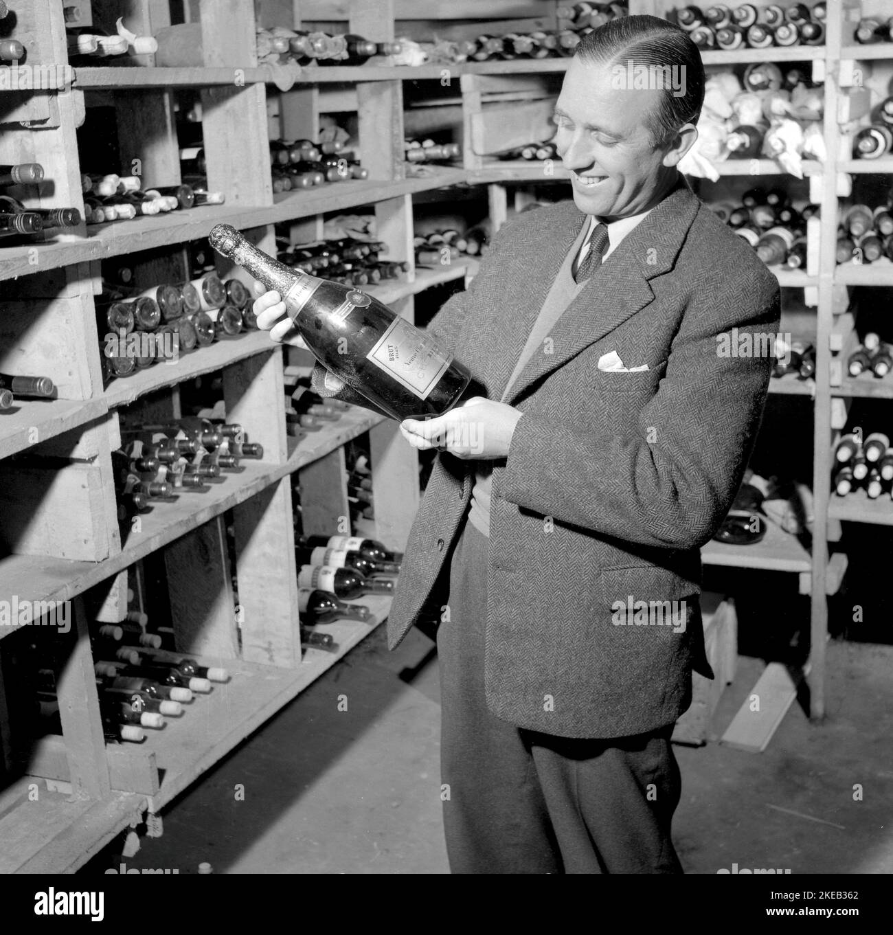 Wine cellar in the 1950s. Hotel Sälen högfjällshotell holds a wine cellar that looks fairly well stocked with bottles in all the shelves. A man holds a bottle of Champagne. A 1945 Veuve Clocquot Ponsardin Vintage Brut. january 10 1954 Sweden. Conard ref 2604 Stock Photo