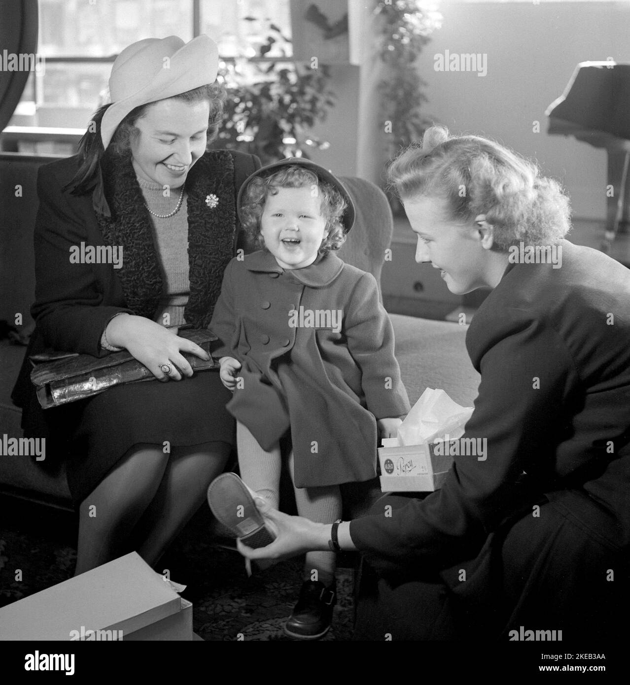 Shoe store in the 1940s. A little girl with her mother in a Stockholm shoe store. She looks happy and smiles when the salesclerk fits the new shoes on her feet.  Sweden 1948. Conard ref 950 Stock Photo