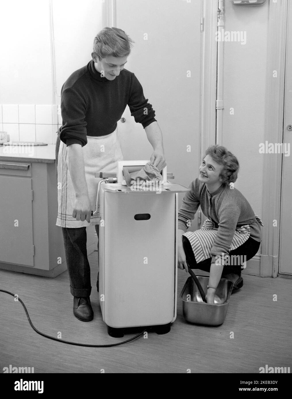 Doing the laundry in the 1950s. A young couple washes their clothes in the Hoover wash machine. The machine had no centrifugation function. The water in the clothes was pressed out manually.   Sweden 1953 ref 2585 Stock Photo