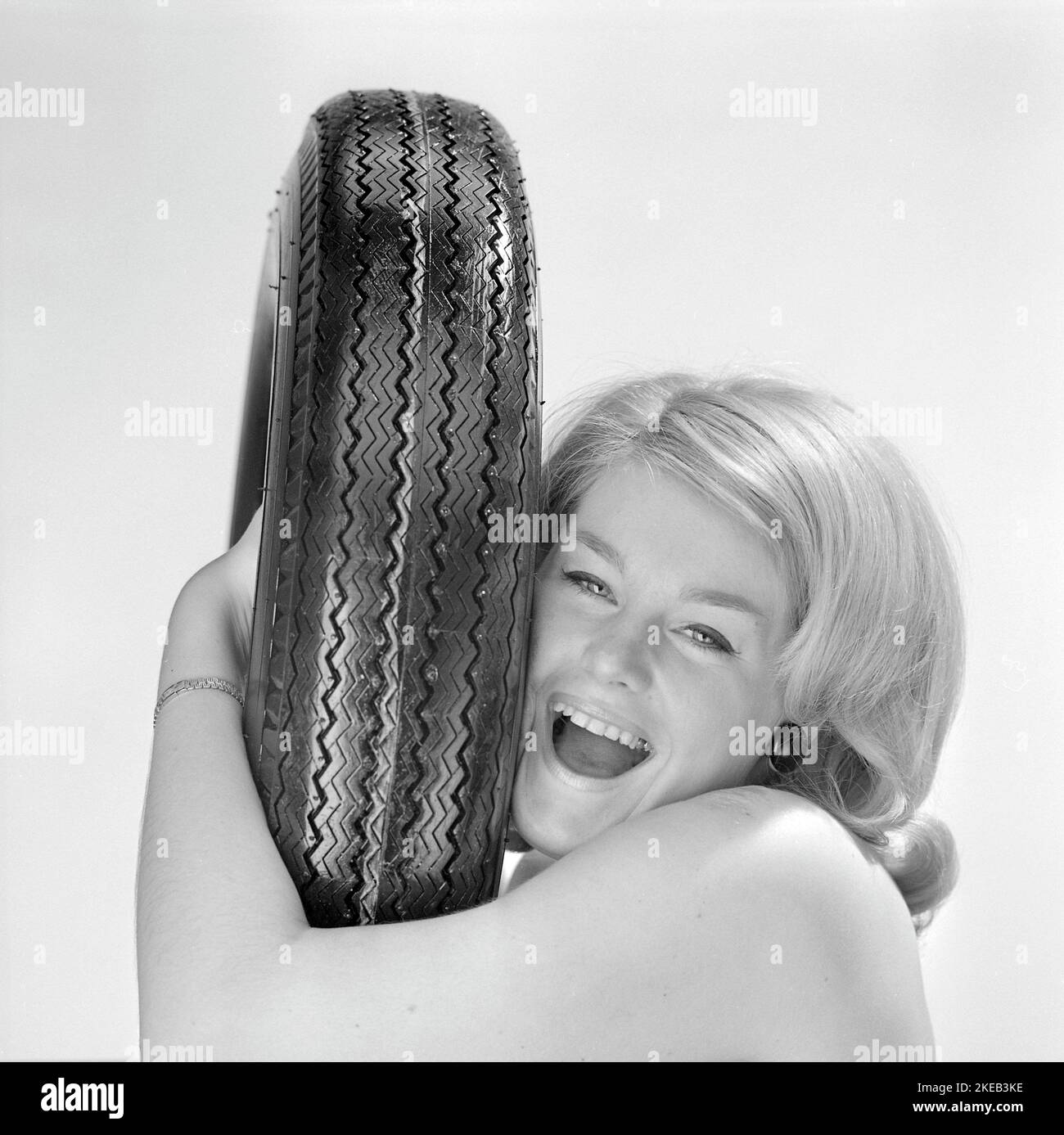 In the 1960s. A young woman with a car tire. Sweden 1967 Stock Photo