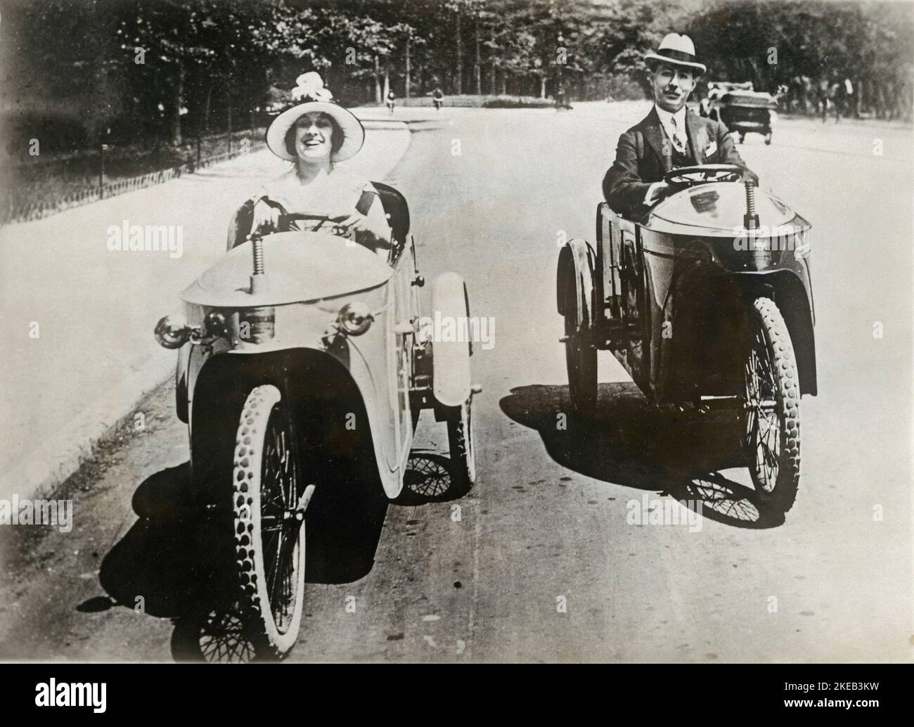 Electric vehicles in the 1930s. Jeny Golden is the star of the show in theatre Casino de Paris. She is pictured driving an electric three wheeld vehicle alongside a gentleman in a similar model. This happened in a Paris street in the 1930s. Stock Photo