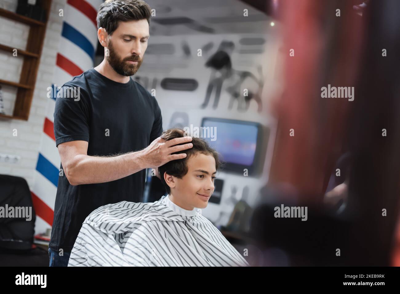 Bearded hairstylist styling hair of smiling teenage boy in beauty salon,stock image Stock Photo