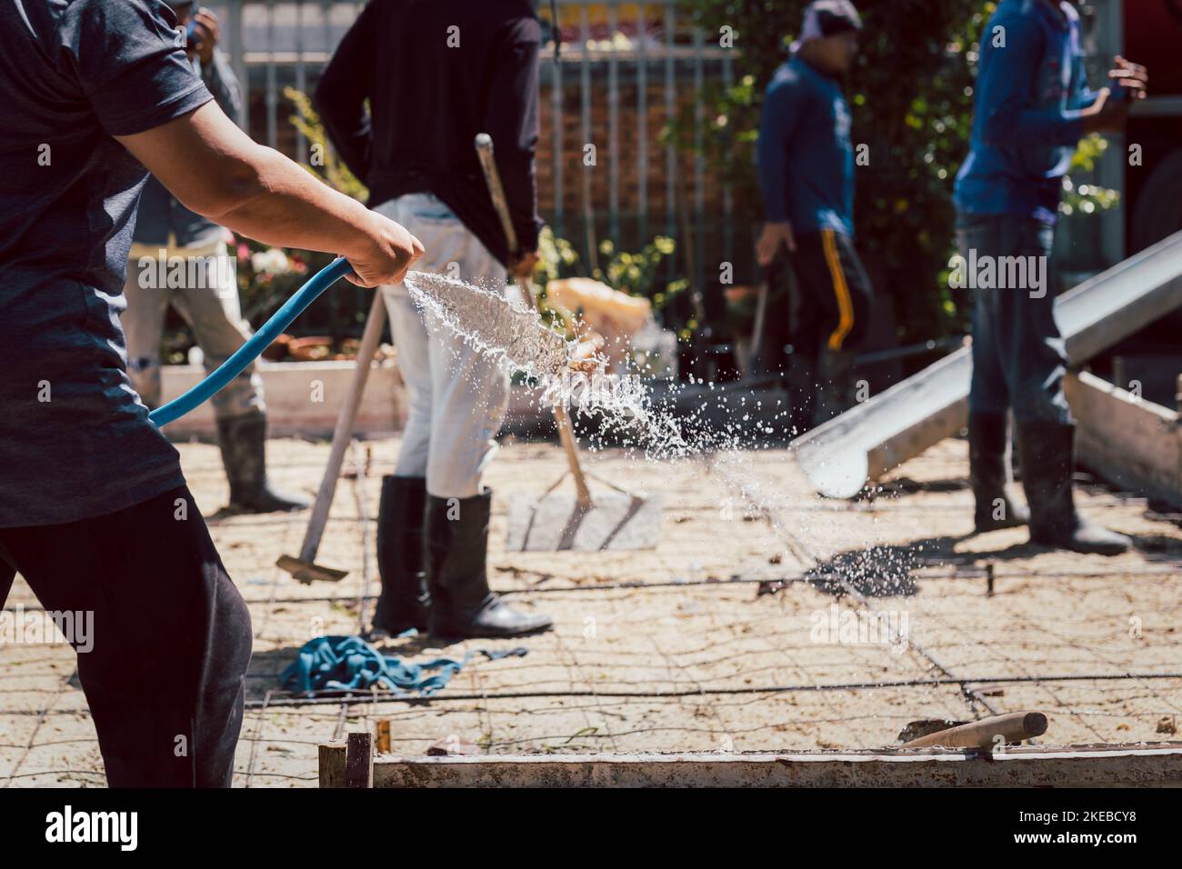 Worker watering ground preparing the concrete in the foundation Stock Photo Alamy