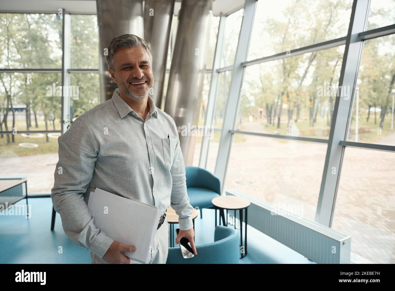 Satisfied middle-aged office employee with a phone and documents Stock Photo