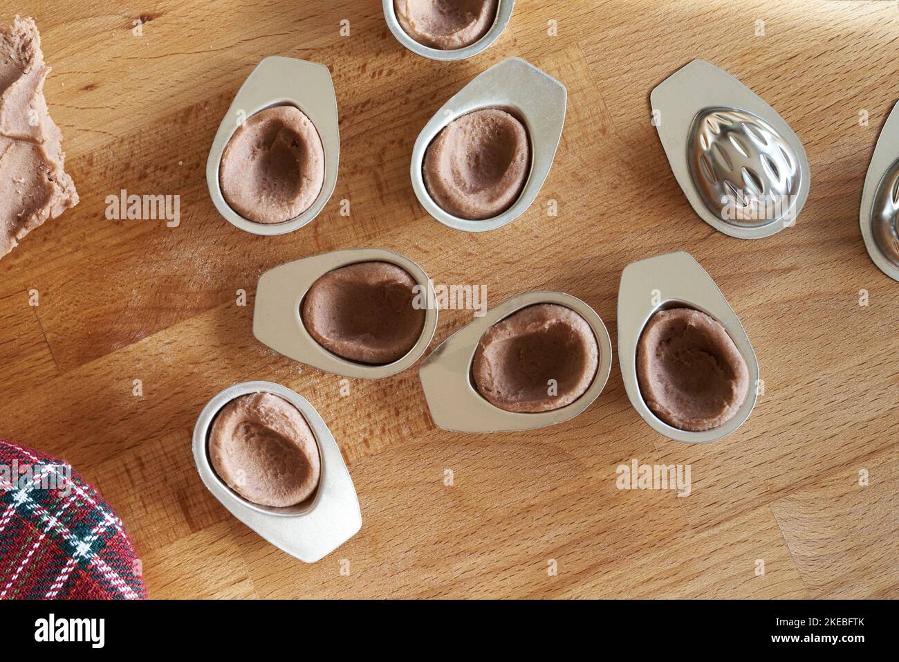 https://c8.alamy.com/comp/2KEBFTK/preparing-homemade-cocoa-christmas-cookies-in-the-form-of-nuts-pressing-the-dough-into-tin-moulds-top-view-2KEBFTK.jpg