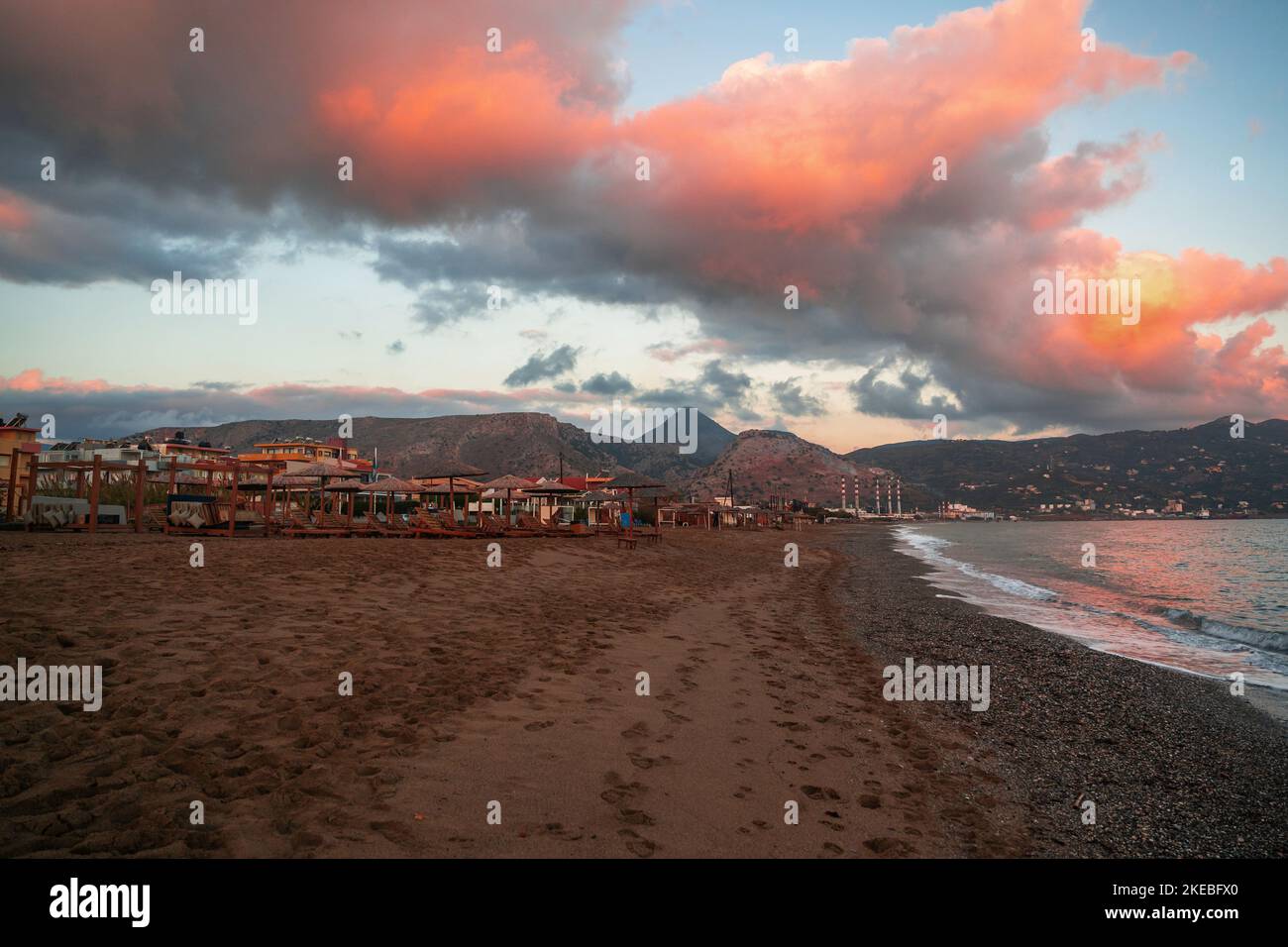 Beach in Amoudara, Crete, in morning sunrise with red cloud and calm sea. Stock Photo