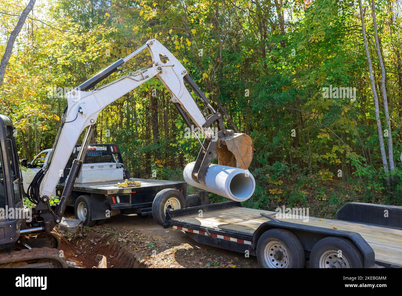 Worker use tractor lift up concrete sewage pipes from truck put down on