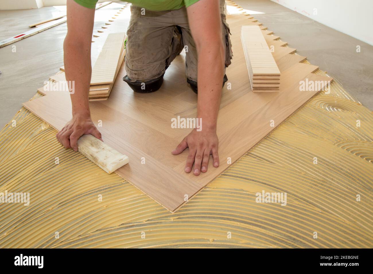 Craftsman laying herringbone parquet flooring professionally Stock