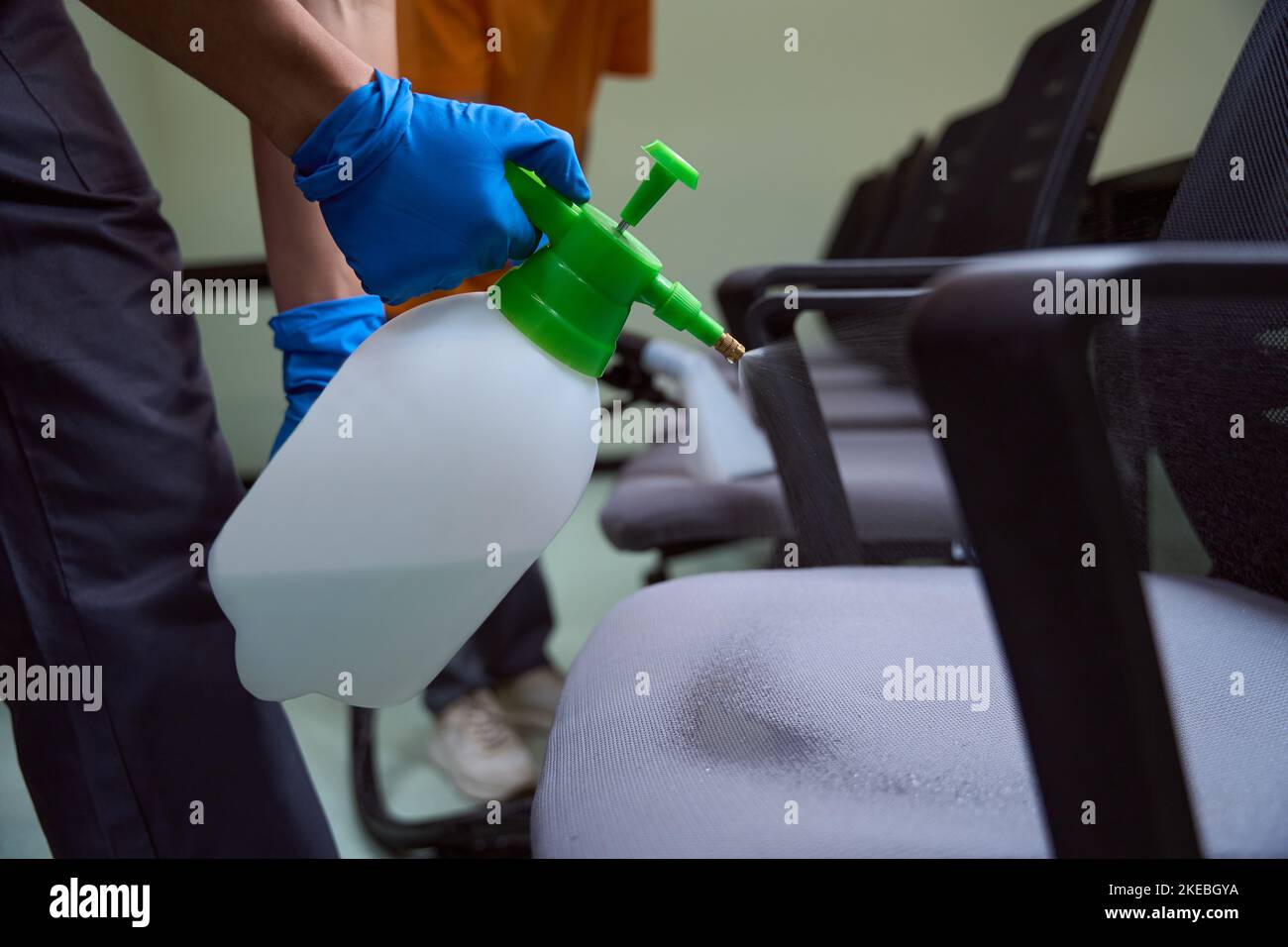 Professional cleaning company worker spraydisinfecting chairs with