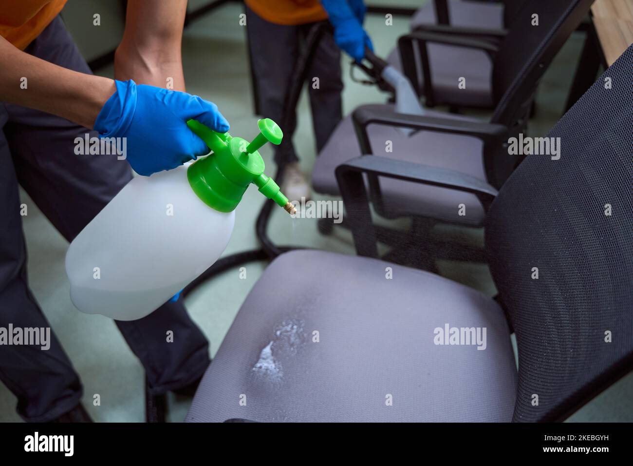 Certified cleaners using disinfectant fluid on furniture Stock Photo