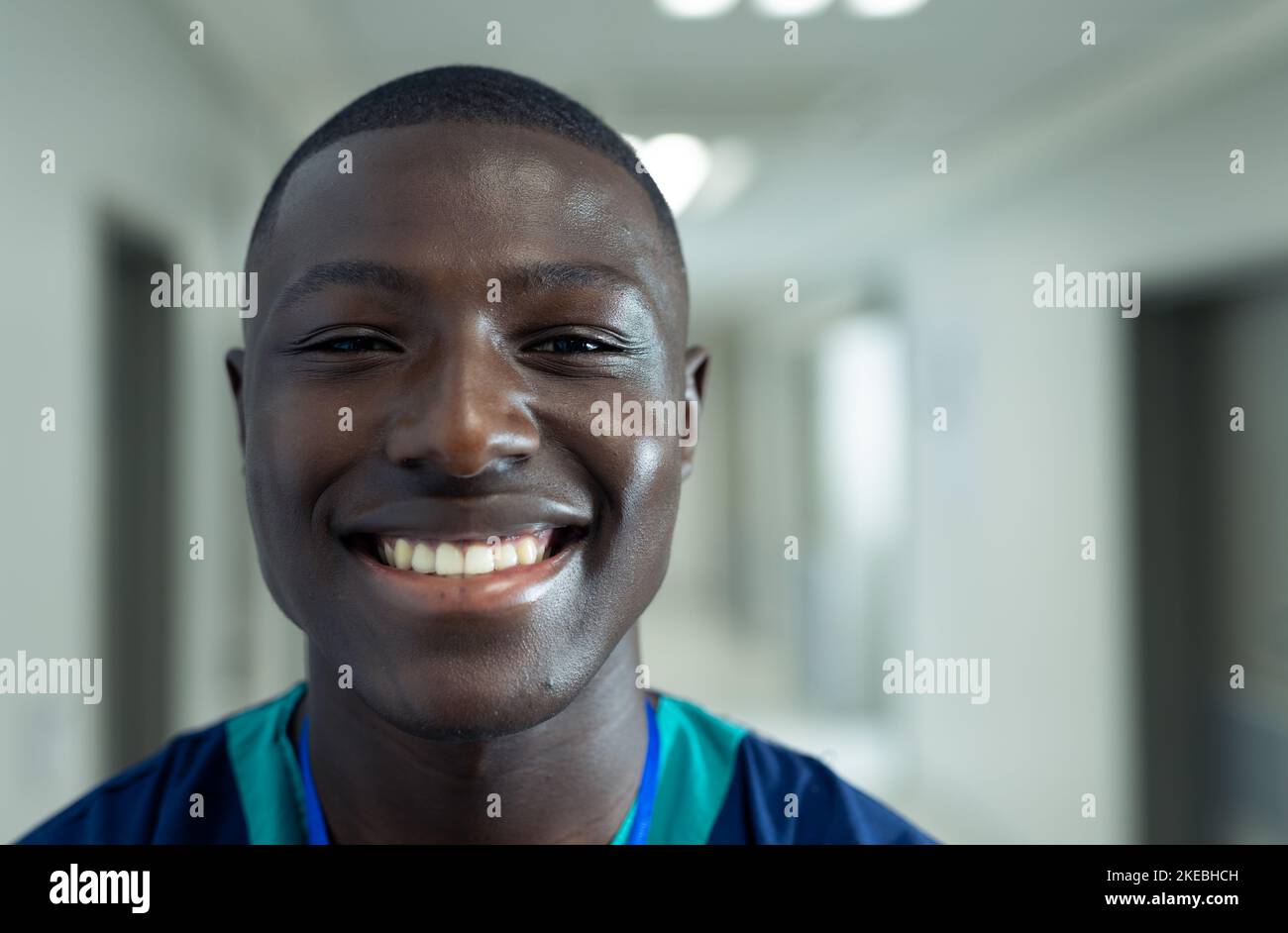 Portrait of smiling african american male healthcare worker in hospital corridor, copy space. Hospital, medical and healthcare services. Stock Photo