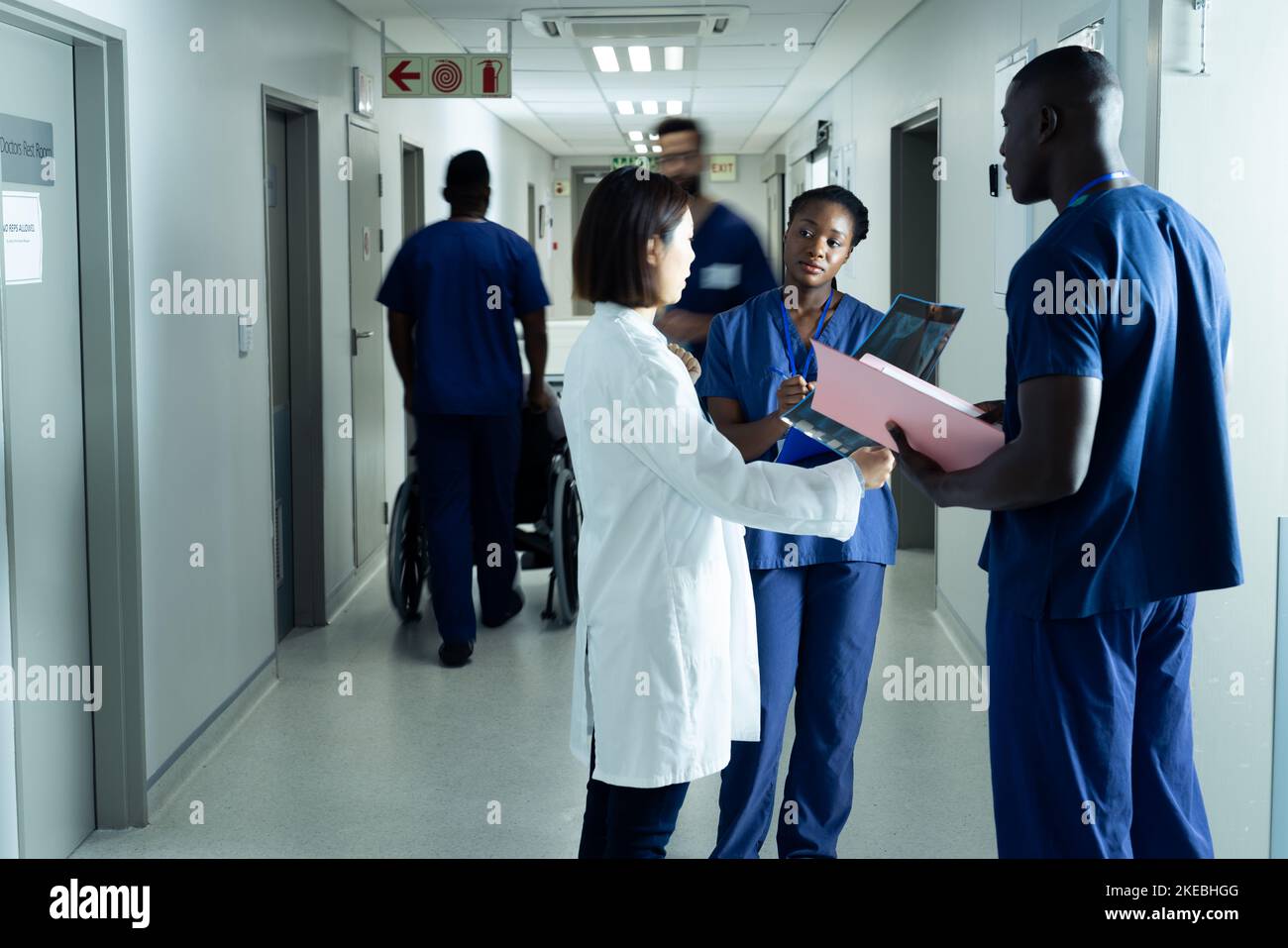 Diverse female doctor and healthcare workers discussing in hospital corridor, copy space Stock Photo