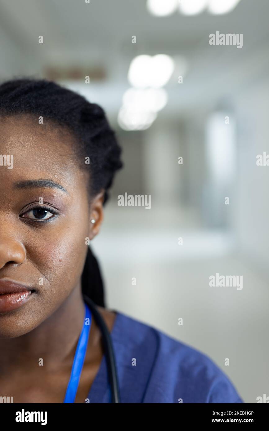 Vertical half face portrait of african american female doctor in hospital corridor, copy space. Hospital, medical and healthcare services. Stock Photo