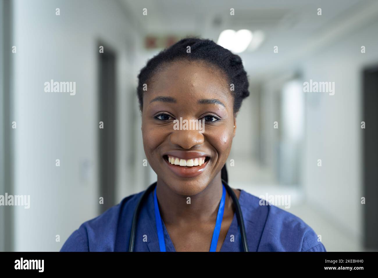 Portrait of smiling african american female doctor in hospital corridor, copy space. Hospital, medical and healthcare services. Stock Photo
