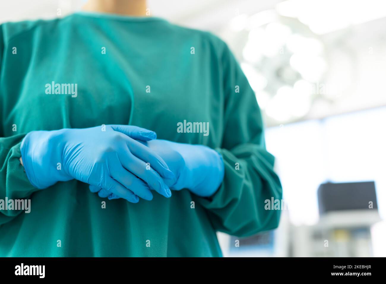 Midsection of female surgeon in blue surgical gloves and green gown