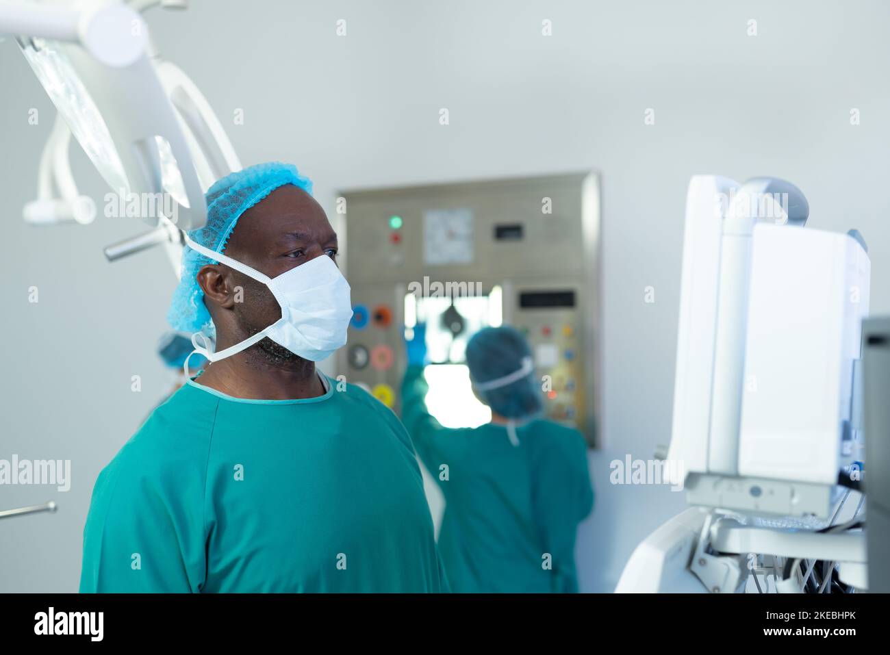 African american male surgeon studying computerised medical equipment in operating theatre. Hospital, medical and healthcare services. Stock Photo