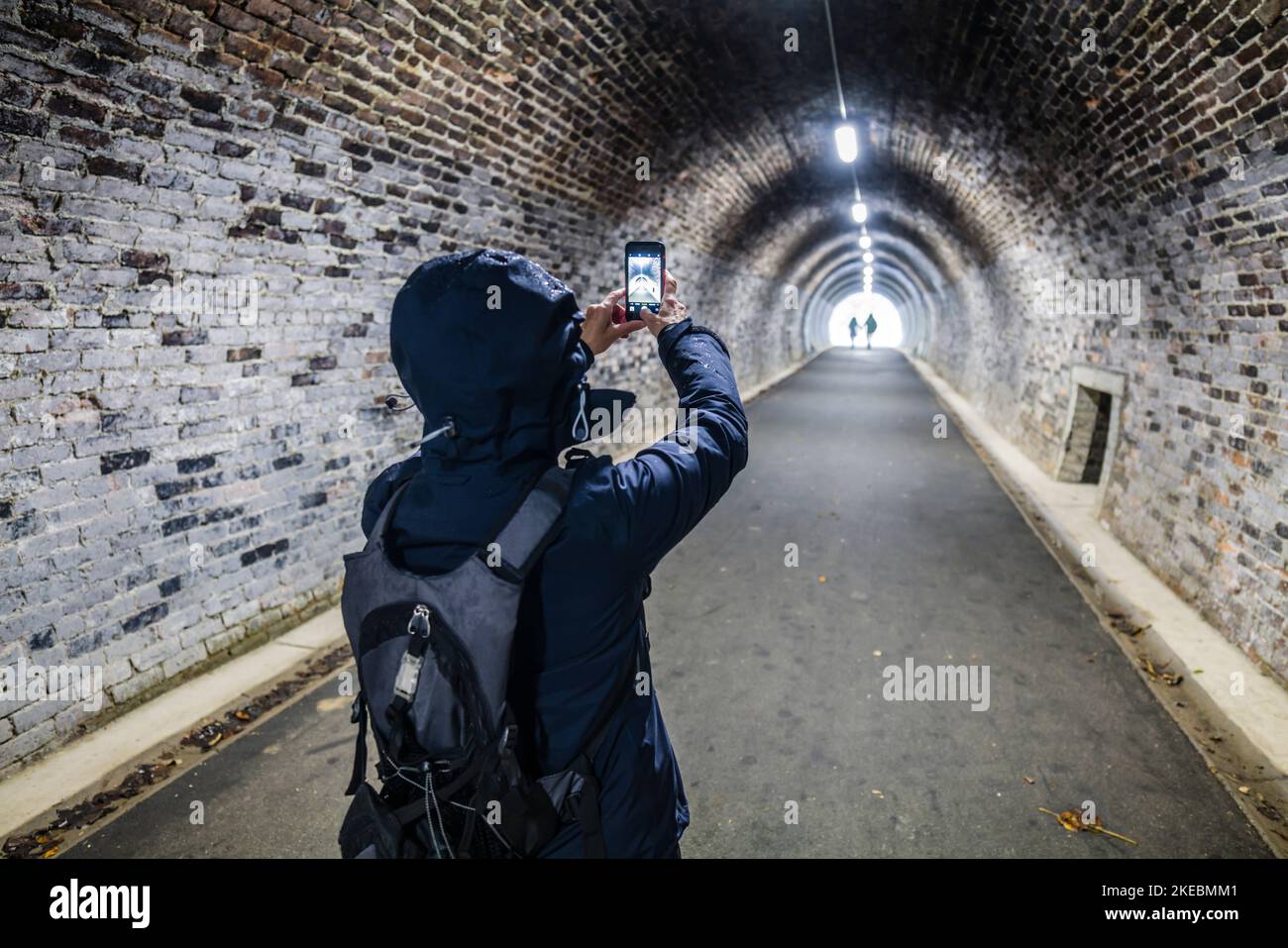 Female photographing in a tunnel on the Keswick rail trail with her mobile phone, English Lake District. Stock Photo