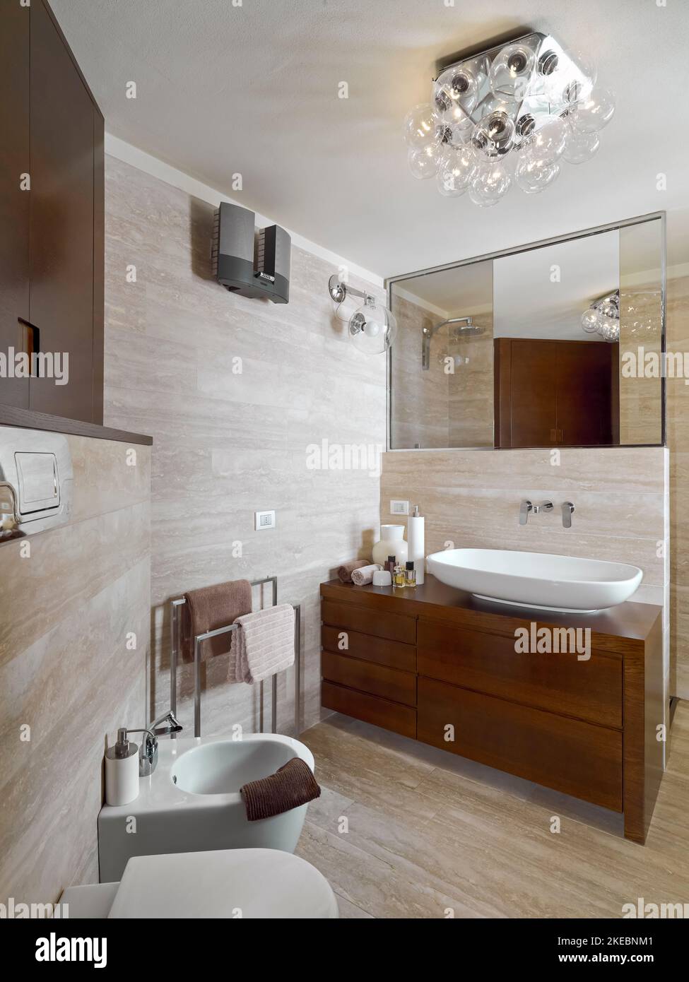 modern interior of the bathroom, in the foreground the bidet and the wooden washbasin cabinet with countertop washbasin, walls and floor are covered i Stock Photo