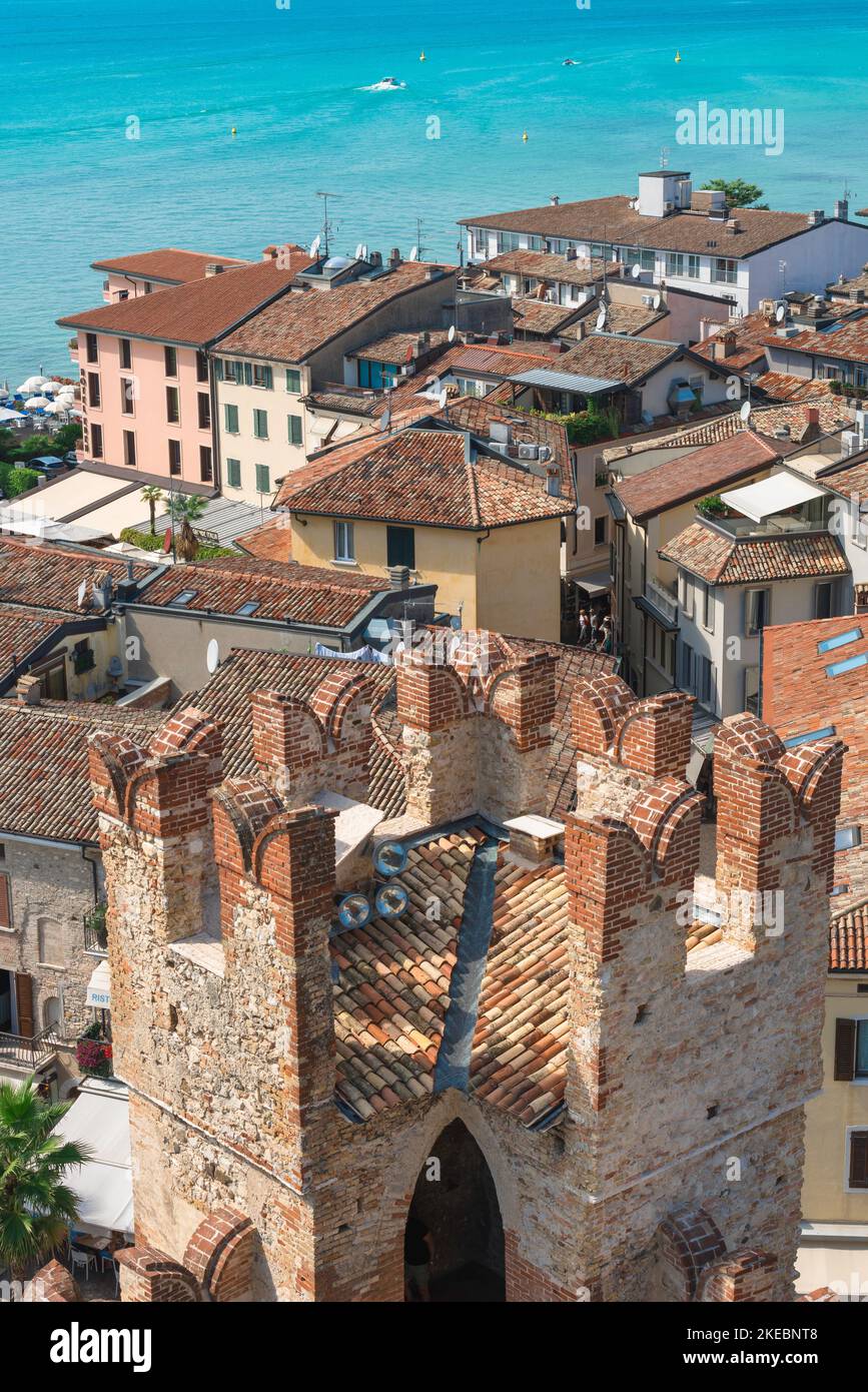 Italian lakes, aerial view in summer across the rooftops of the scenic lakeside town of Sirmione showing a tower of the Scaligero Castle, Lake Garda Stock Photo