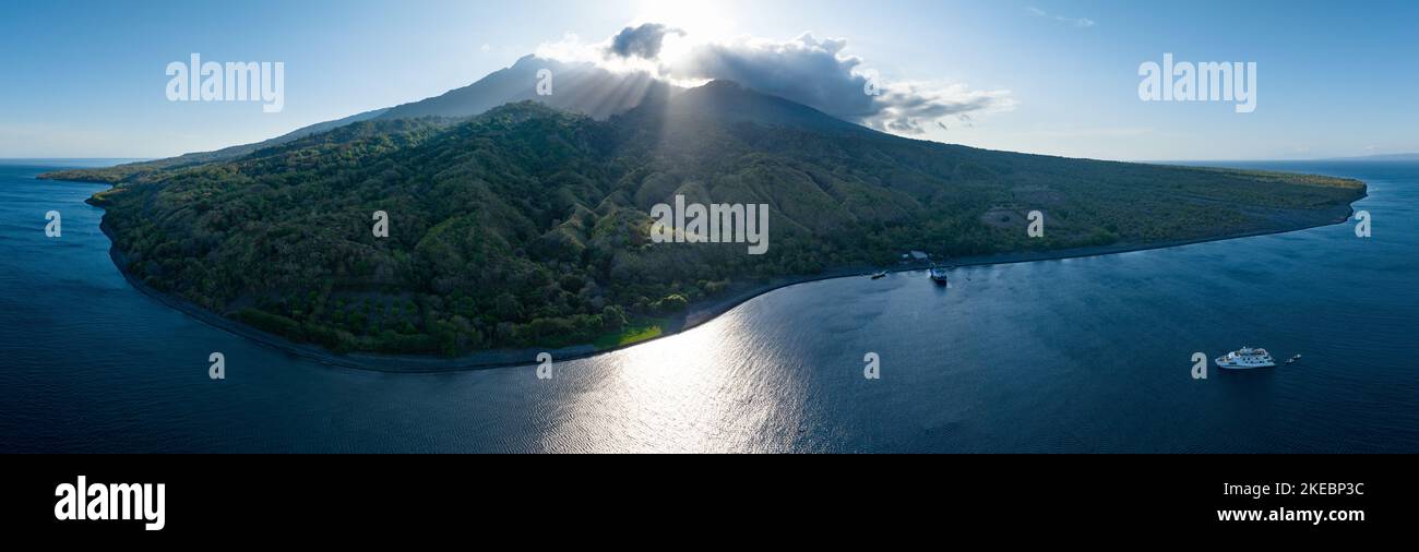 The sun rises behind the impressive volcano of Sangeang, found just outside of Komodo National Park, Indonesia. This area has high biodiversity. Stock Photo