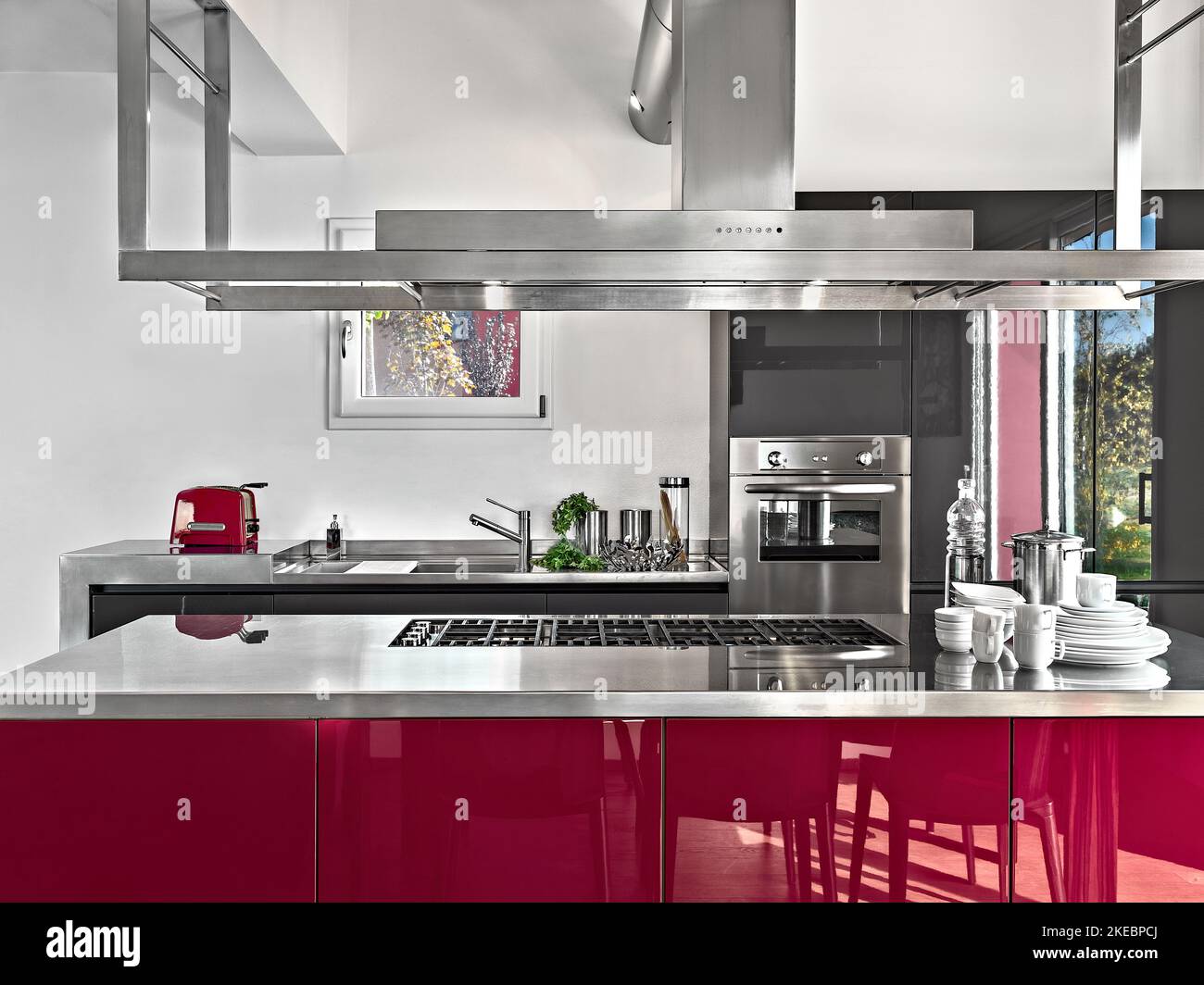 interior of a modern kitchen in the foreground the island kitchen with gas hob and the extractor hood in the background the integrated oven and the si Stock Photo